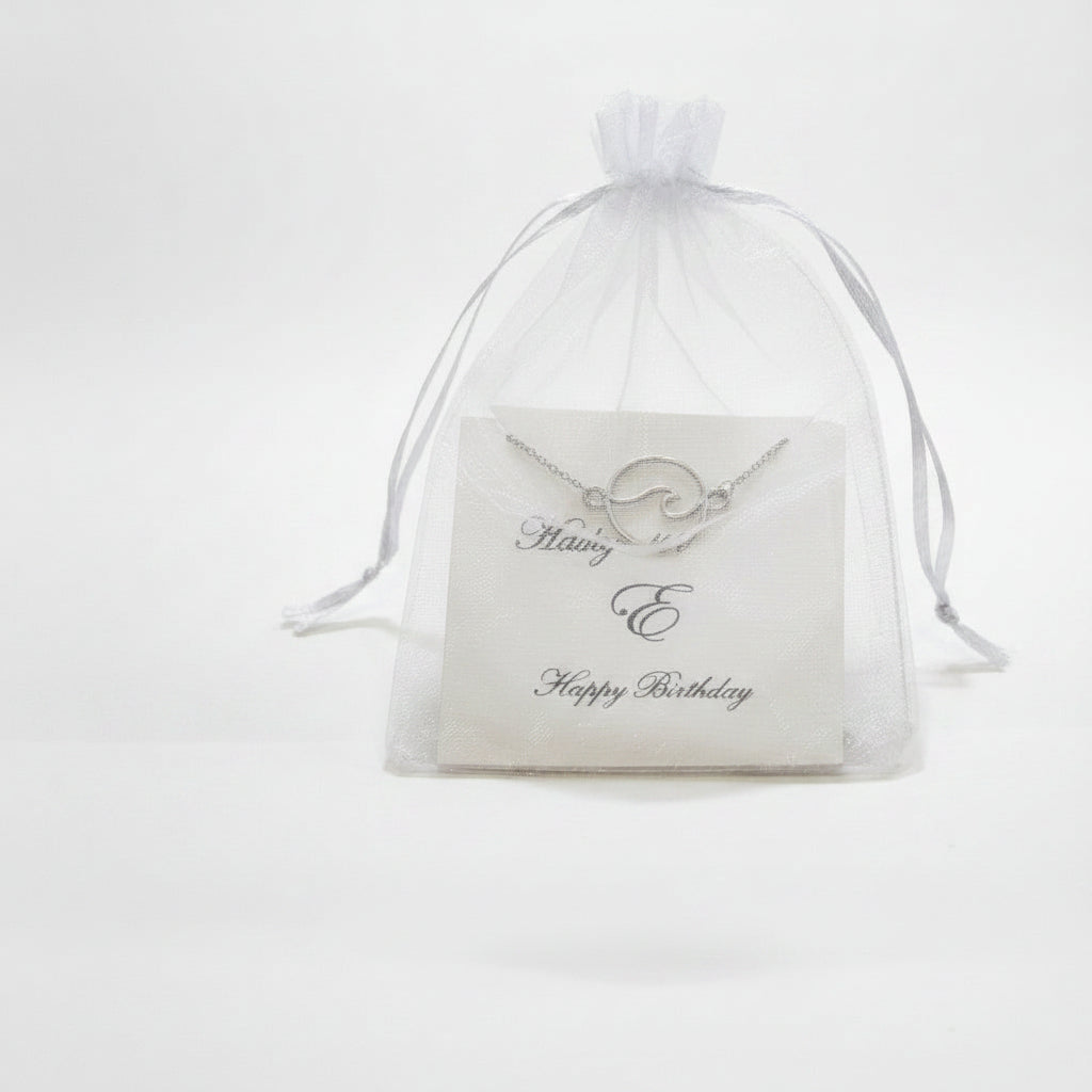 Clear drawstring bag with a silver necklace and card on a white background JIA Jewellery